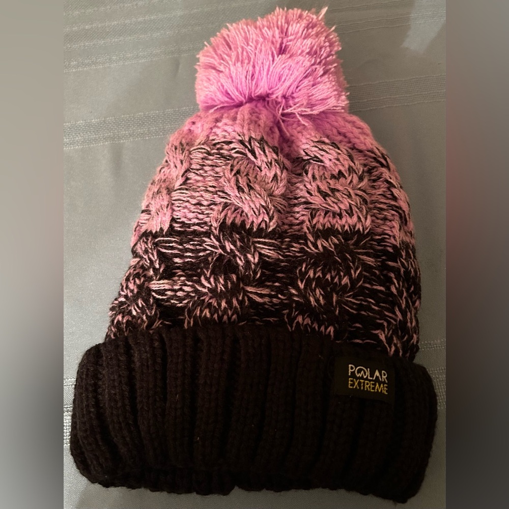 Polar Extreme cable knit beanie with a pom pom and pink and black coloring.
